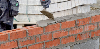 Construction worker laying bricks for a masonry foundation