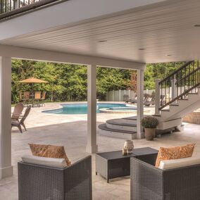 A photo of a beautiful backyard patio with elevated deck, shielding the below patio from rain using the rain escape system