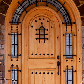 Pictured is a curved custom door by Dallas Millwork featuring iron over glass