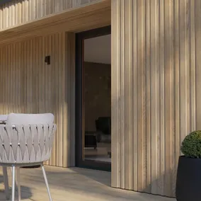 A modern home exterior featuring Millboard G Board and Batten siding in Golden Oak, showcasing a warm, natural wood aesthetic with vertical paneling