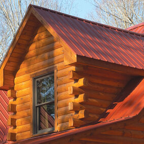 Pictured is an orange reddish colored metal roof on a log cabin
