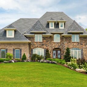 Stone veneer home with multiple roof elevations, and a lush green yard