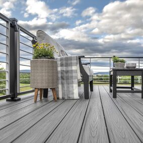 A view of a deck looking upward at the sky. There is a seating area with a coffee table and a couch with white cushions. A flower arrangement is next to the seating area.