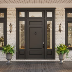 Classic traditional entry door to home in the color black, with greenery on each side