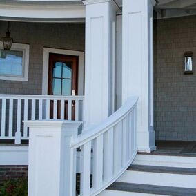 Exterior porch featuring large intex column covers with a sweeping railing