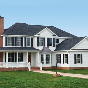 Exterior of large white home featuring black open louver shutters