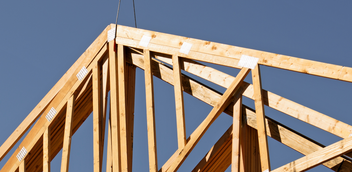 Pictured is a pair of wood trusses hanging in the air before being placed.